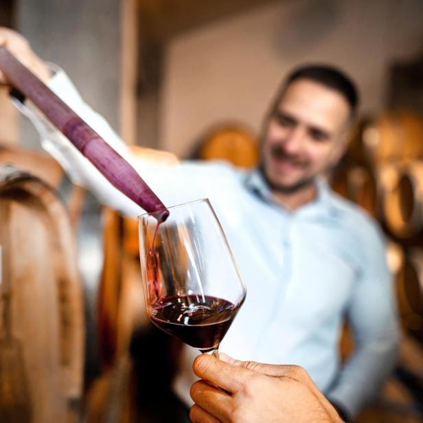 Wein wird mit einem Weinheber in ein Glas gefüllt.