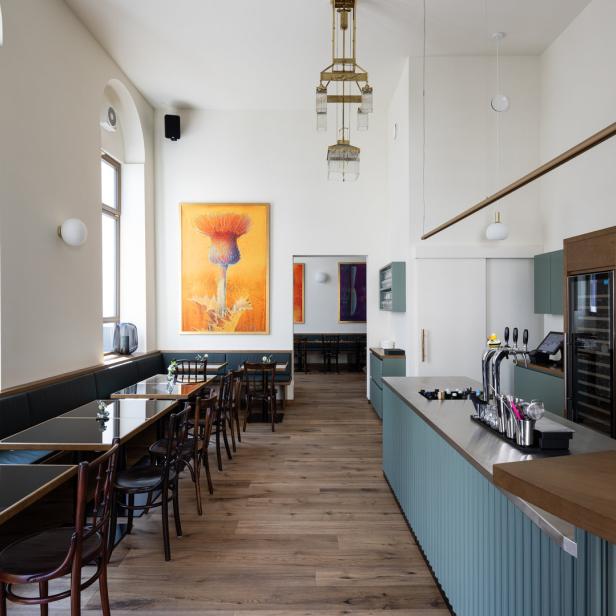 Innenansicht eines Restaurants mit Bar, Tischen und einem Gemälde einer Distel.