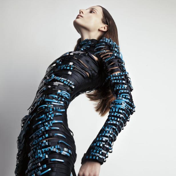 Eine Frau präsentiert ein futuristisches, schwarzes Kleid mit blauen Akzenten.