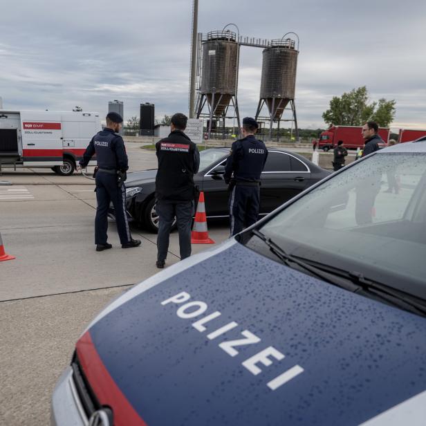 Polizisten kontrollieren ein Auto an einer österreichischen Grenze.
