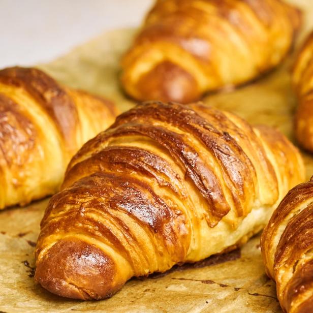 Mehrere goldbraune Croissants liegen auf Backpapier.