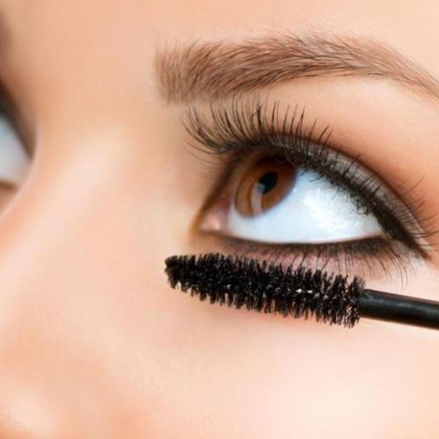 Eine Frau tuscht sich die Wimpern.