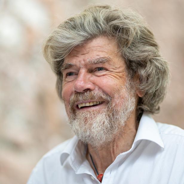 Reinhold Messner lächelt in einem weißen Hemd.