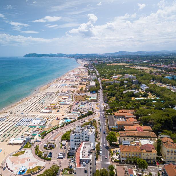 Luftaufnahme eines Küstenortes mit Strand, Meer und angrenzender Bebauung.
