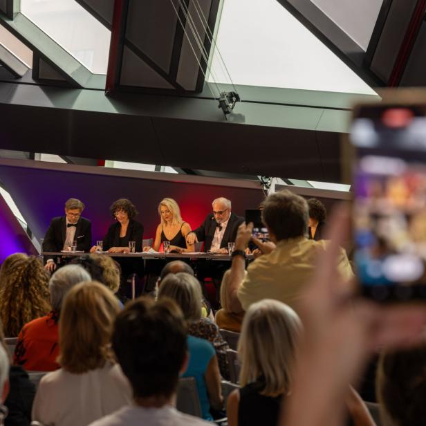Eine Podiumsdiskussion mit mehreren Personen vor einem Publikum.