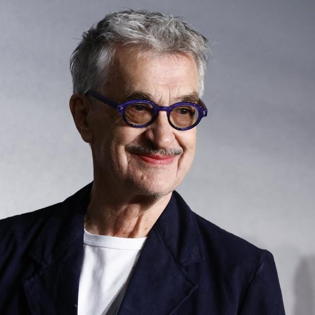 Der deutsche Schauspieler Udo Kier mit lila Brille lächelt.
