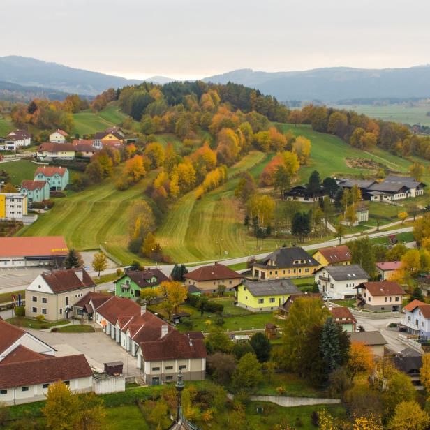 Ein Blick auf eine ländliche Gemeinde mit bunten Häusern und herbstlichen Bäumen.