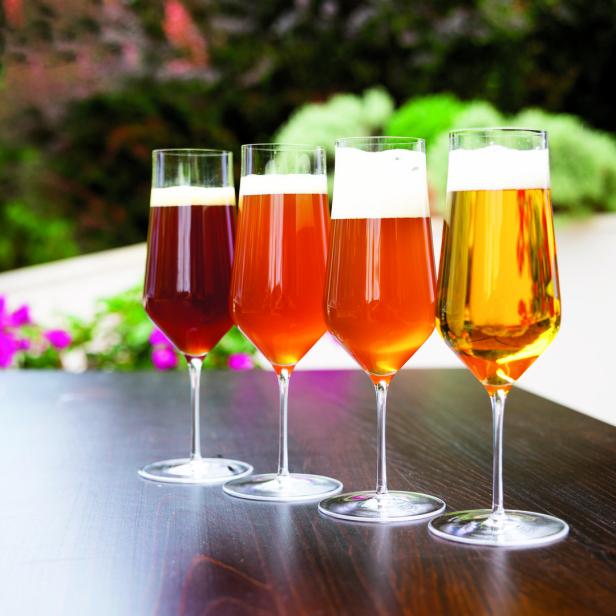 Vier Gläser mit unterschiedlichen Biersorten stehen auf einem Tisch.