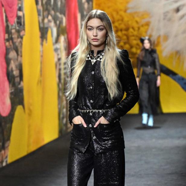 Gigi Hadid läuft in einem glitzernden schwarzen Hosenanzug über einen Laufsteg.