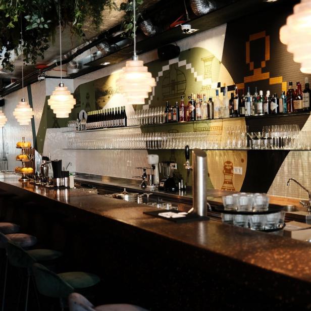 Eine Bar mit Hockern, Getränken und dekorativen Lampen.