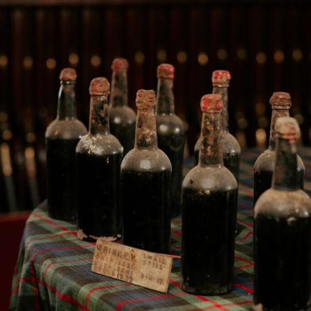 Alte Whiskeyflaschen stehen auf einem karierten Tuch.