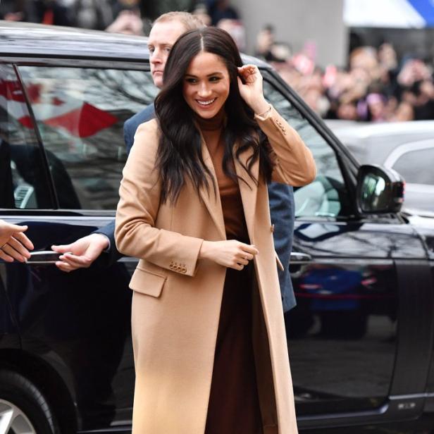 Meghan Markle verlässt ein Auto in einem beigen Mantel und braunen Schuhen.