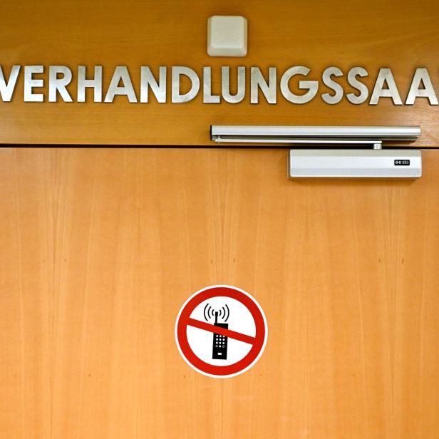 Die Tür zu einem Verhandlungssaal mit einem Verbotsschild für Mobiltelefone.