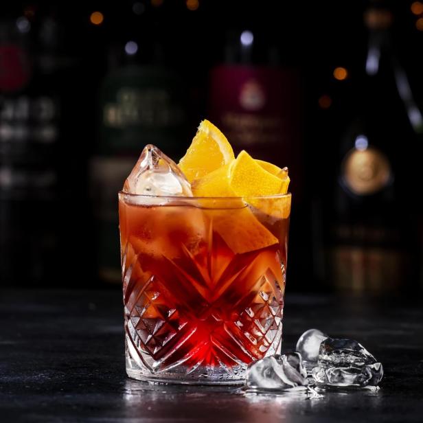 Negroni-Cocktail mit Eis und Orangenscheiben in einem Kristallglas.
