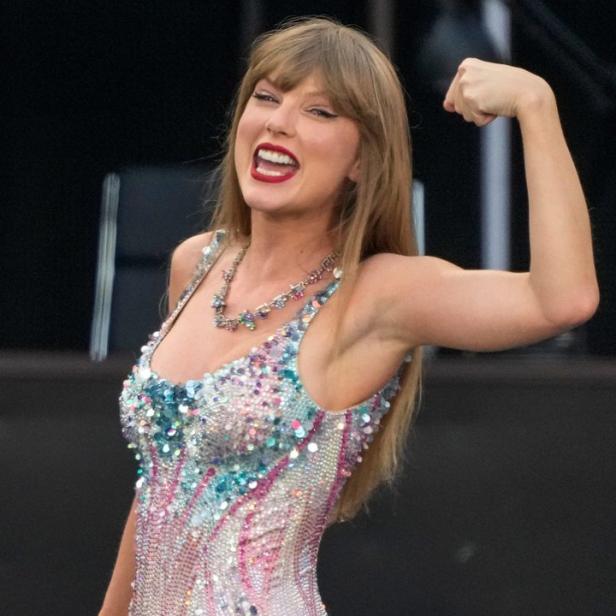 Taylor Swift posiert in einem glitzernden Body und zeigt ihren Bizeps.