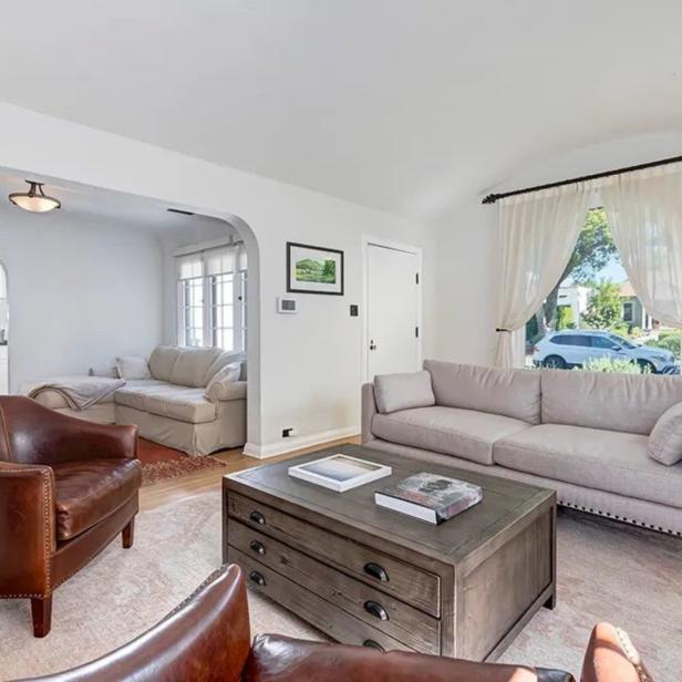 Ein Wohnzimmer mit hellen Wänden, einem grauen Sofa und zwei braunen Ledersesseln.