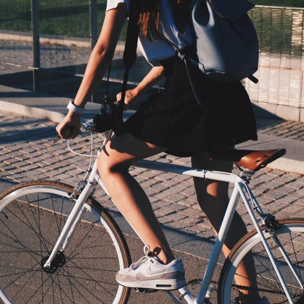 Eine Frau fährt mit einem weißen Fahrrad auf der Straße.