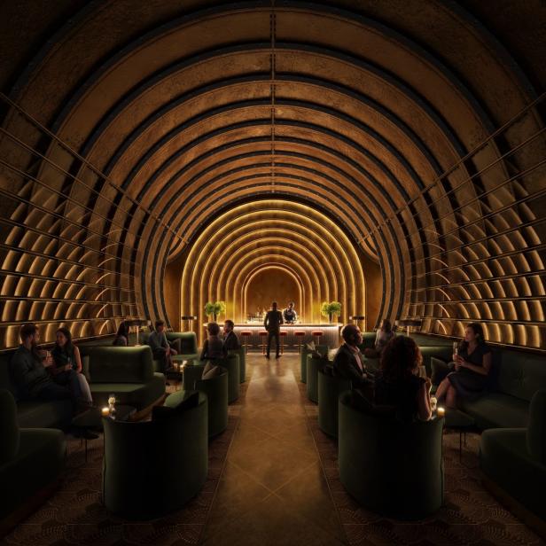 Ein Tunnel-ähnlicher Raum mit einer Bar und sitzenden Gästen in grünen Sesseln.