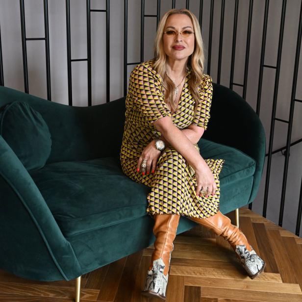 Anastacia sitzt für ein Interview auf einem grünen Sofa.