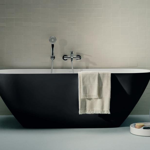 Eine schwarze Badewanne mit einem weißen Handtuch hängt an der Seite.