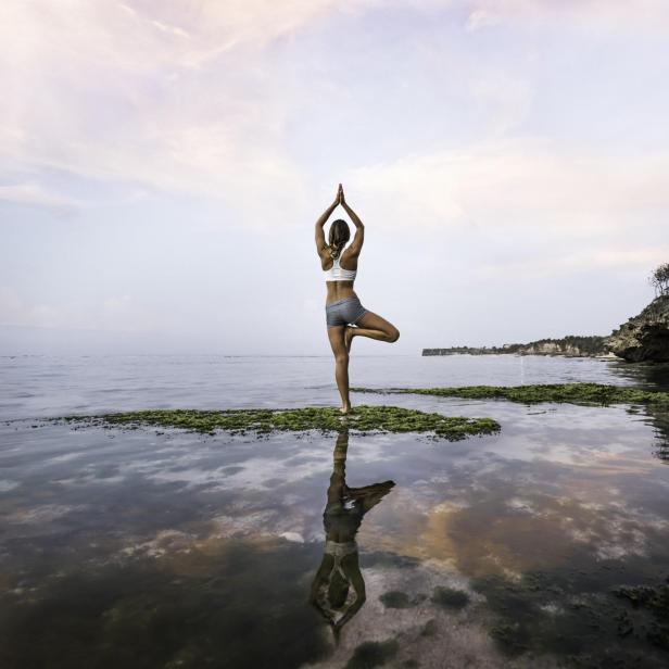 Frau praktiziert Yoga am See.