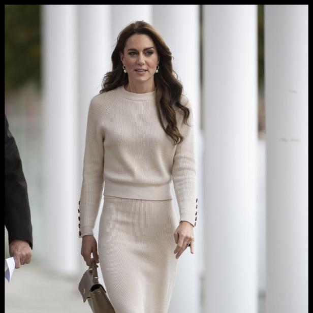 Prinzessin Kate geht mit einer Handtasche in der Hand.