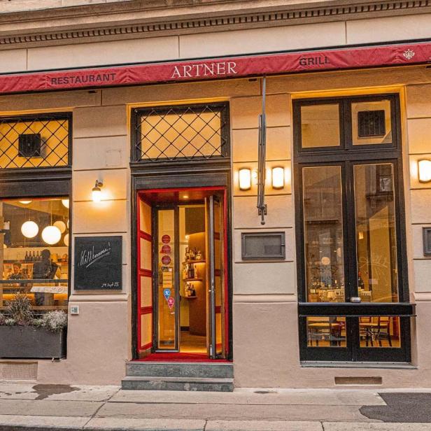 Die Fassade des Restaurants Artner mit roter Markise und einladendem Eingangsbereich.