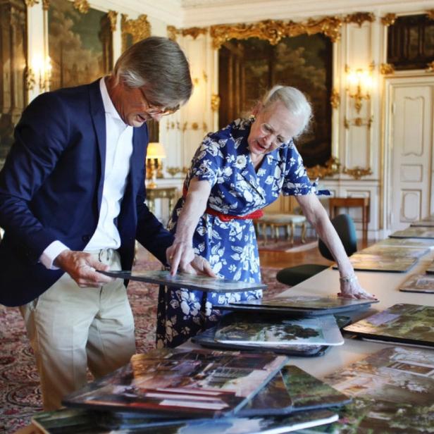 Königin Margrethe II. von Dänemark betrachtet mit einem Mann Landschaftsbilder.