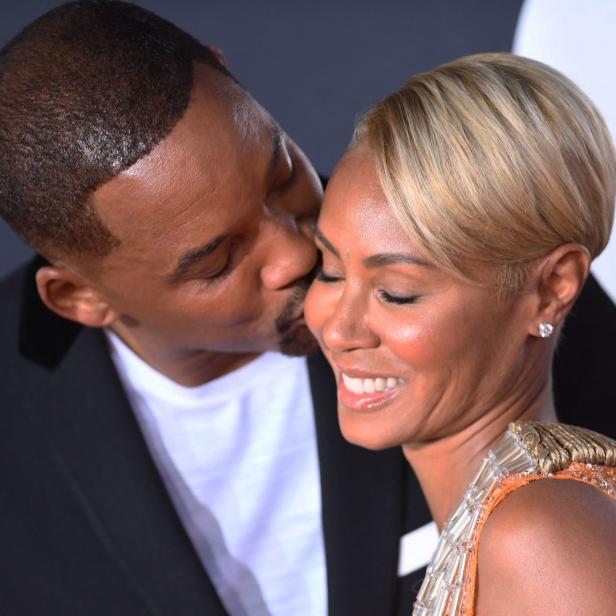 Will Smith küsst Jada Pinkett Smith auf die Wange.