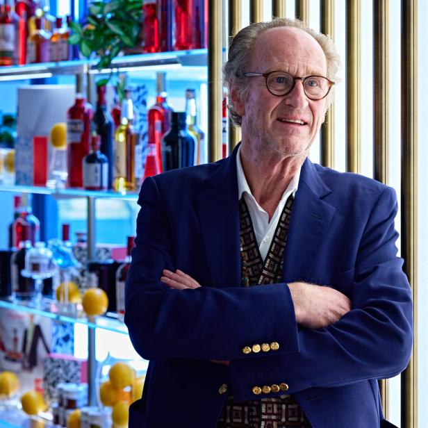 Ein Mann mit Brille und blauem Sakko steht vor einer Bar.