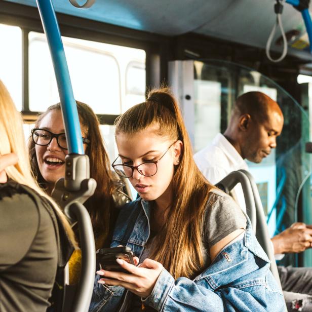 Mehrere Personen fahren mit einem Bus und benutzen ihre Smartphones.