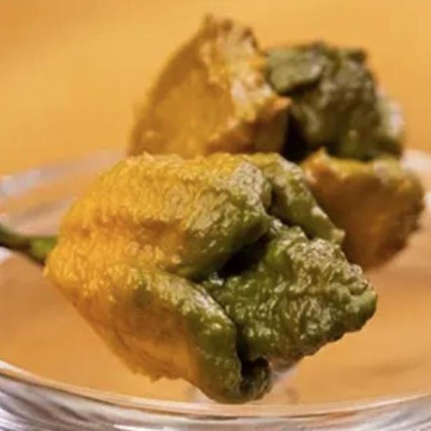 Zwei grüne und gelbe Carolina Reaper Chilis liegen in einer Glasschale.
