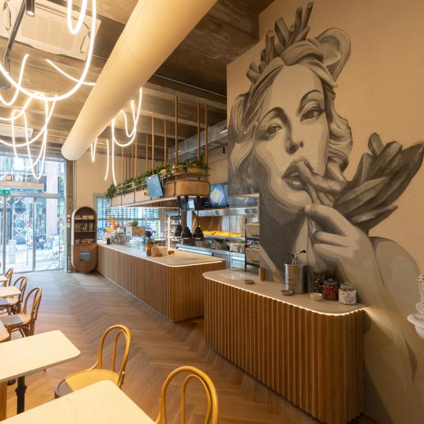 Innenansicht eines Restaurants mit einem großen Wandgemälde einer Frau.