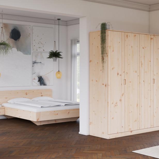 Ein Schlafzimmer mit einem Holzbett und einem großen Kleiderschrank aus hellem Holz.