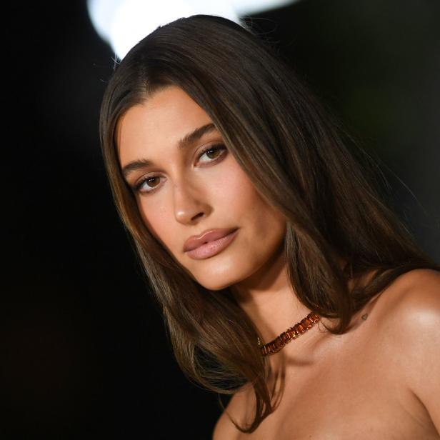 Porträt von Hailey Bieber mit braunen Haaren und einer orangefarbenen Halskette.