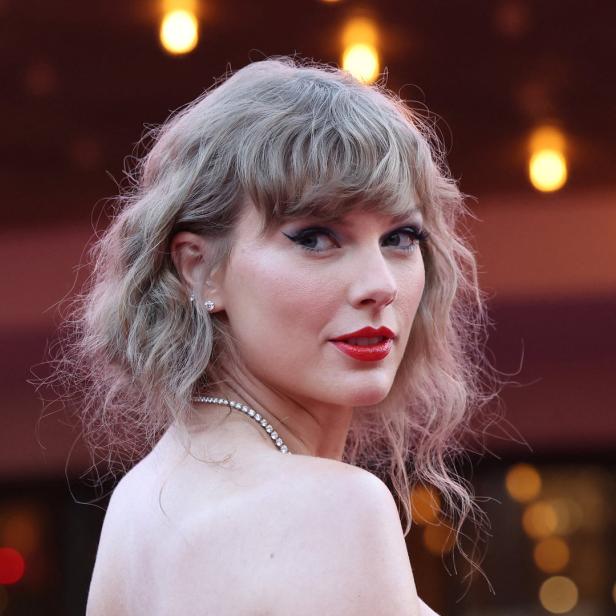 Ein Porträt von Taylor Swift mit roten Lippen und blond gelocktem Haar.