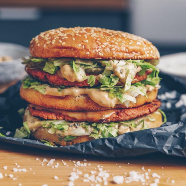 Ein großer, veganer Big Mac mit Salat und Soße.
