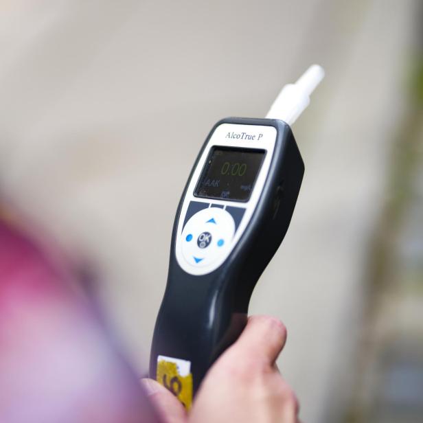 Eine Person hält ein Alkoholmessgerät in der Hand.