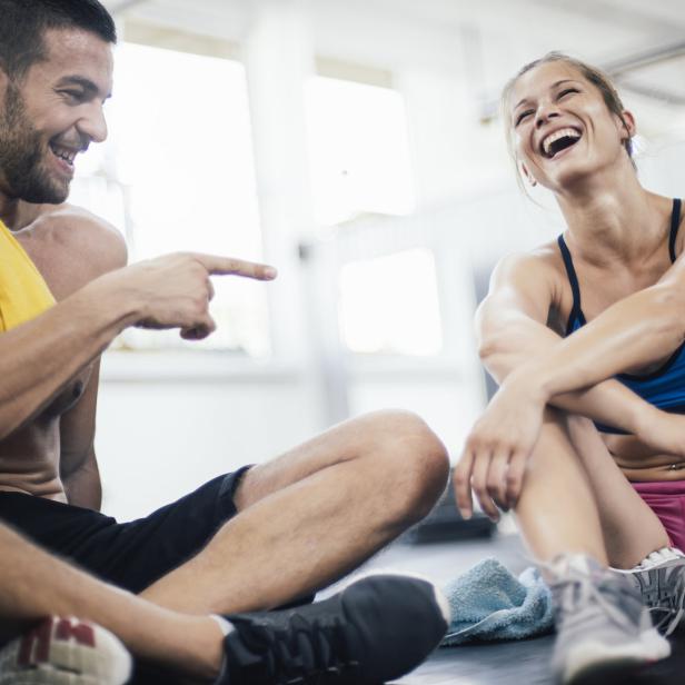 Eine Frau und ein Mann sitzen lachend nach dem Sport zusammen.