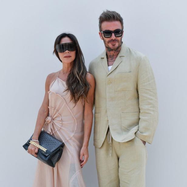 Victoria und David Beckham posieren vor einer weißen Wand.