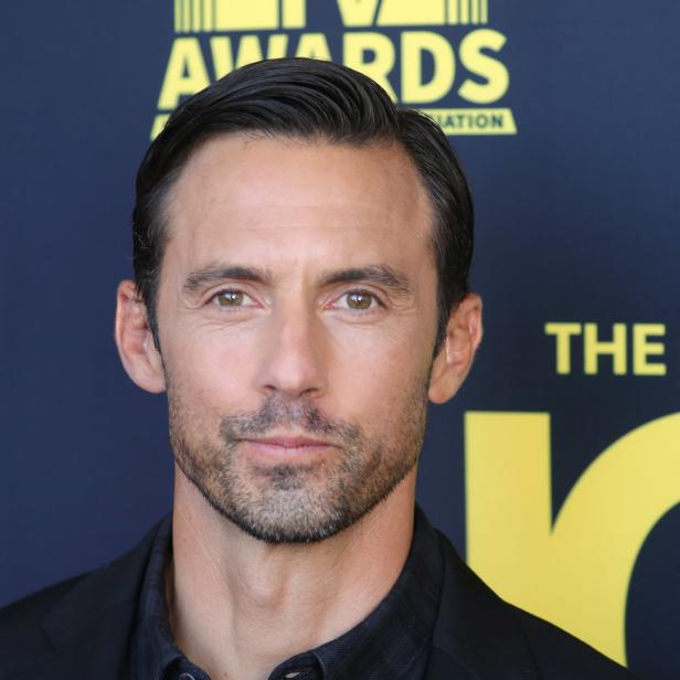 Milo Ventimiglia posiert vor einem dunkelblauen Hintergrund mit gelber Schrift.