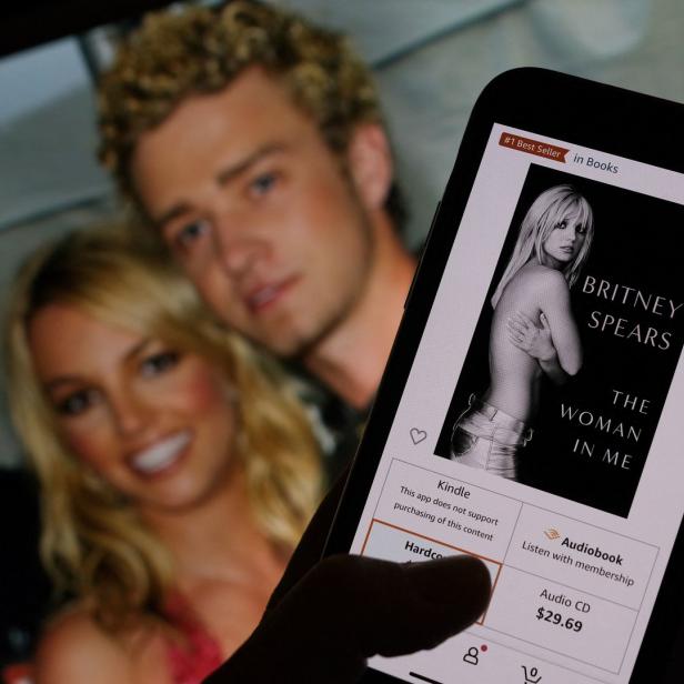 Ein Smartphone zeigt das Buch „The Woman in Me“ von Britney Spears; im Hintergrund ein Foto von ihr und Justin Timberlake.