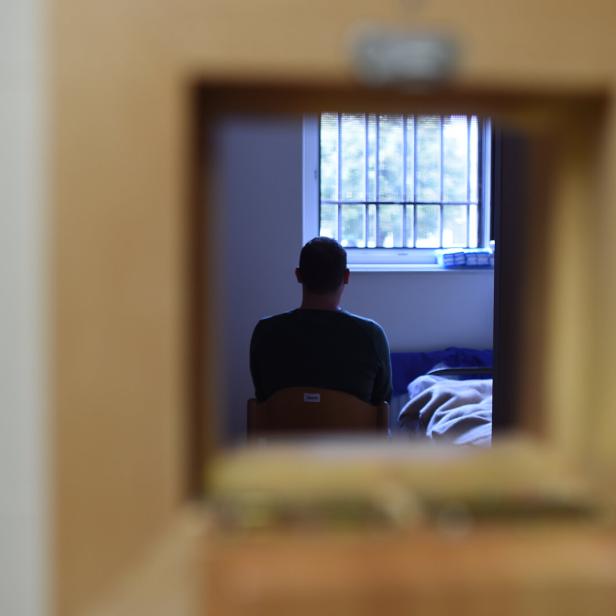 Justizanstalt: Ein Mann sitzt in einem Raum vor einem vergitterten Fenster.