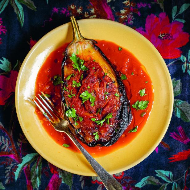 Eine gefüllte türkische Aubergine mit Tomatensoße und Petersilie auf einem Teller.