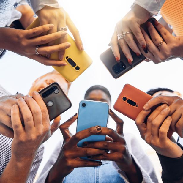 Jugendliche stehen im Kreis und halten Smartphones in der Hand.