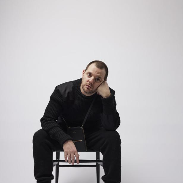 Der Rapper Mike Skinner sitzt auf einem Stuhl.