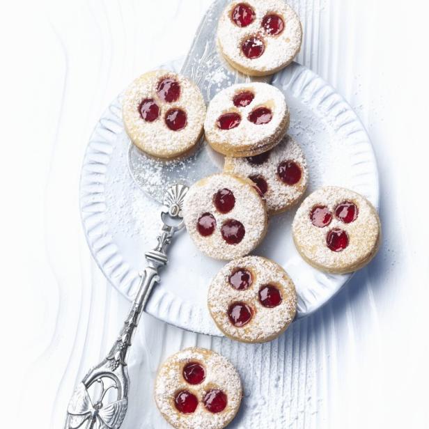Auf einem Teller liegen Linzer Augen mit Puderzucker bestäubt.