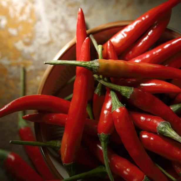 Viele rote Chilischoten liegen in einer Schale.