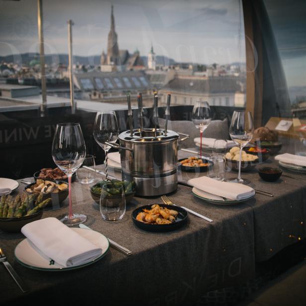 Ein Tisch mit Fondue-Zutaten und Blick auf Wien.