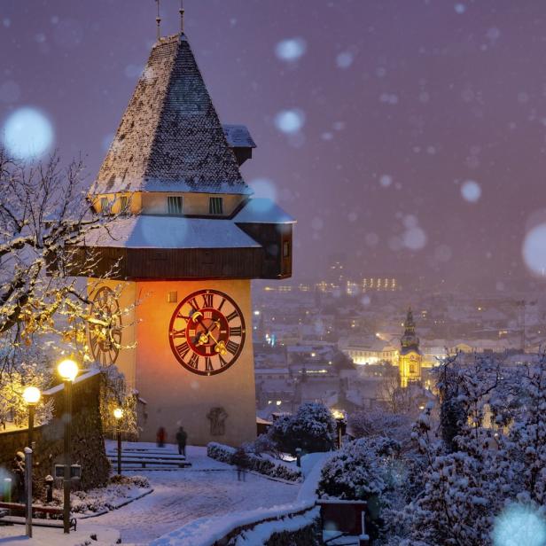 Der Grazer Uhrturm und die verschneite Stadt im Winter.